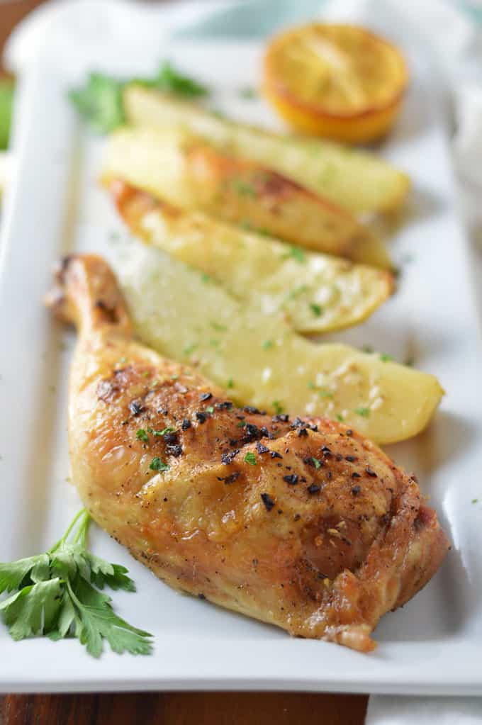 A close up of roasted chicken and potatoes on a plate.