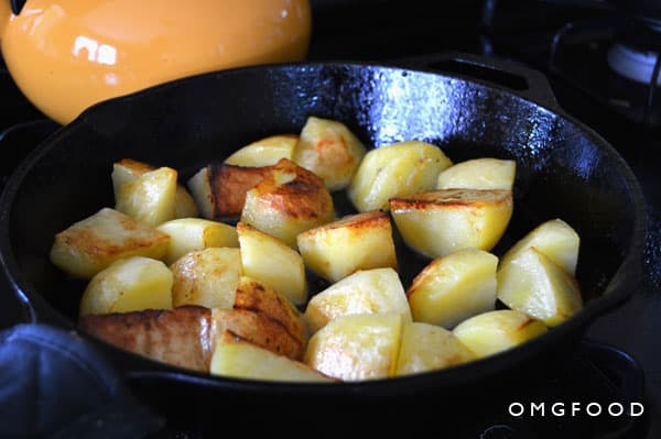 Potato pieces cooking in a skillet.