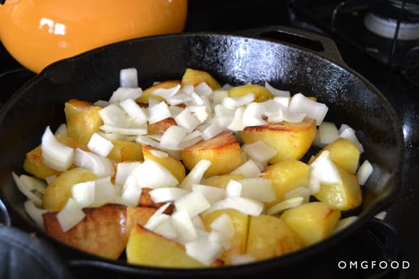 Diced potatoes and onions cooking in a skillet.