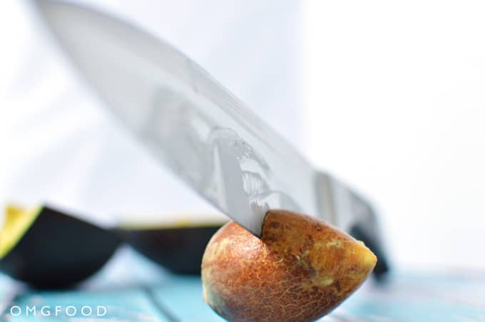 Closeup of a chef\'s knife in an avocado pit.