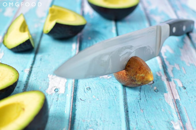 A chef\'s knife in an avocado pit.