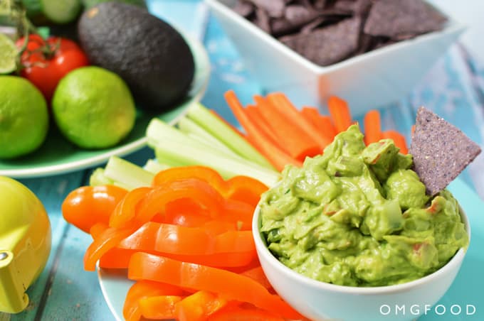 A bowl of guacamole with veggie sticks.