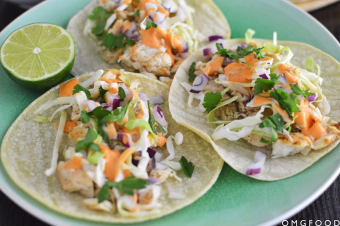 Closeup of three fish tacos on a plate.