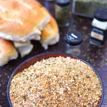 Bead crumbs in a bowl with bread and spices in the background.