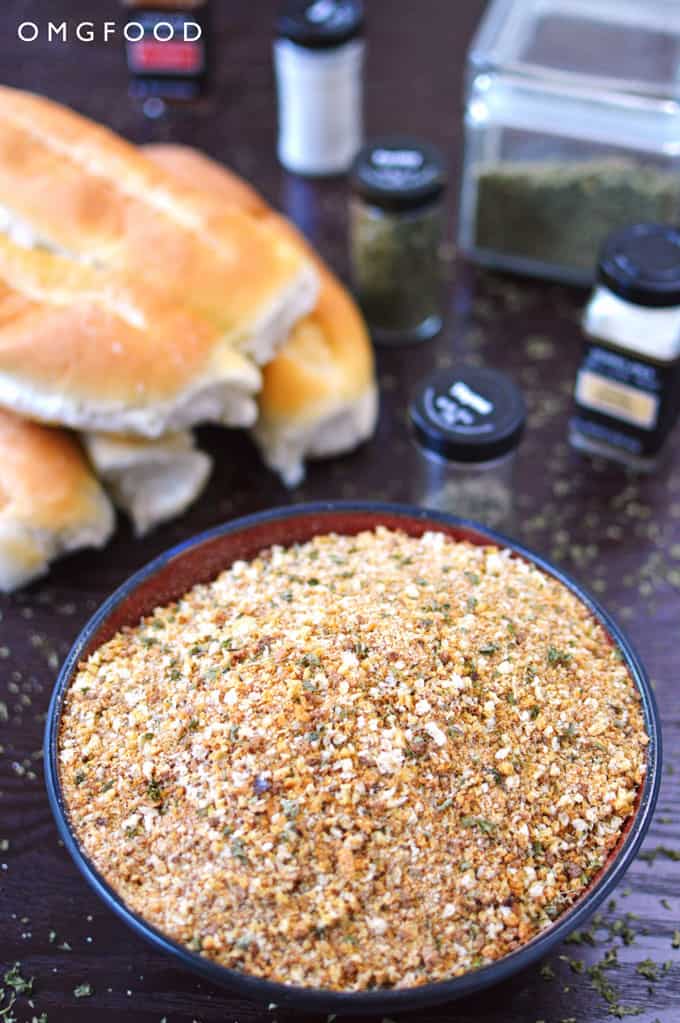 Bead crumbs in a bowl with bread and spices in the background.