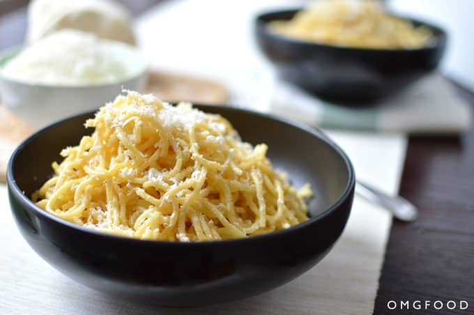 Close up of spaghetti in a bowl with grated cheese.