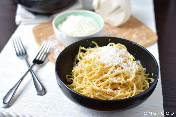 A bowl of spaghetti with grated cheese.