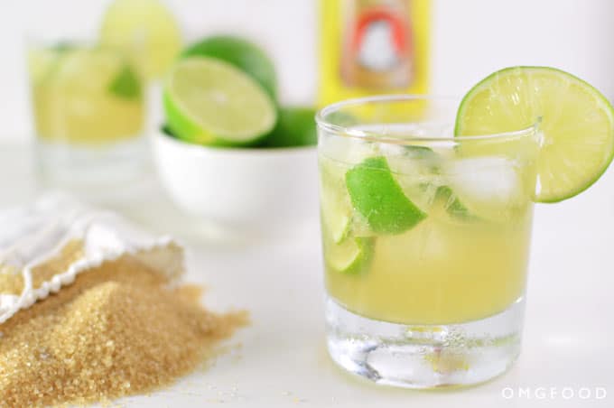 A closeup of a drink in a cocktail glass with limes.