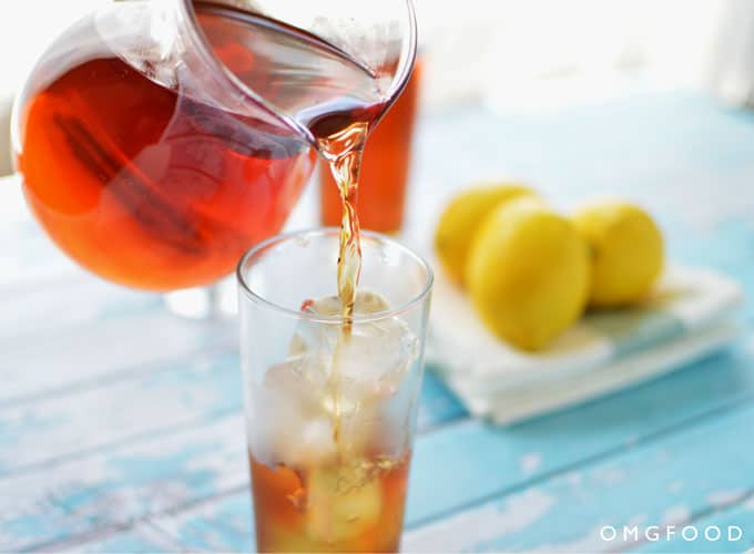 Iced tea being poured over ice in a drinking glass.