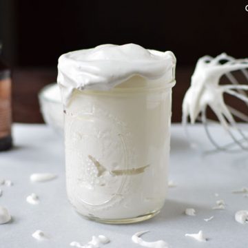 Marshmallow sauce in a glass mason jar on a tabletop.