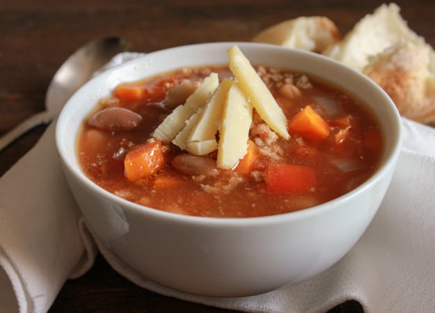 A bowl of bean soup topped with cheese.