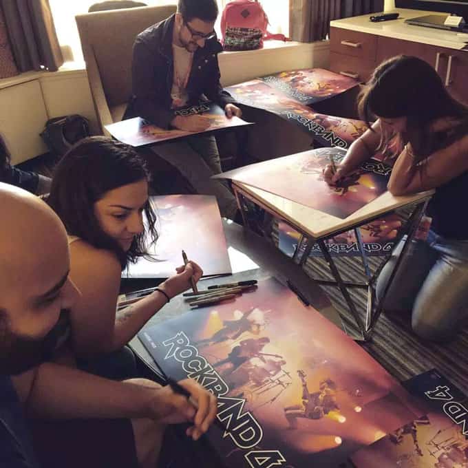 A group of people sitting at tables with posters and markers.