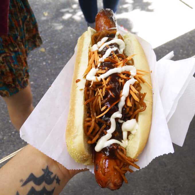 A hand holding a loaded hot dog.