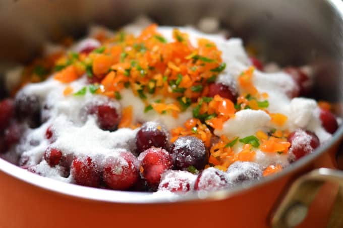 Cranberries in a saucepan topped with sugar and minced chile peppers.