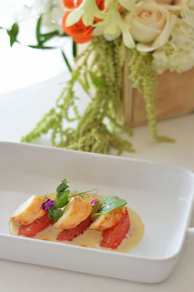 Scallops on a plate with a flower box in the background.