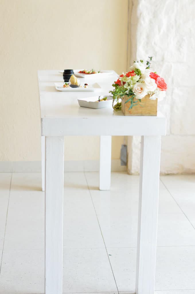 A table topped with a flower box and plates of food.