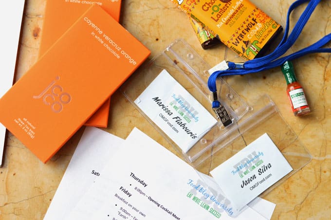 Assorted papers, name tags, and chocolate bars on a tabletop.