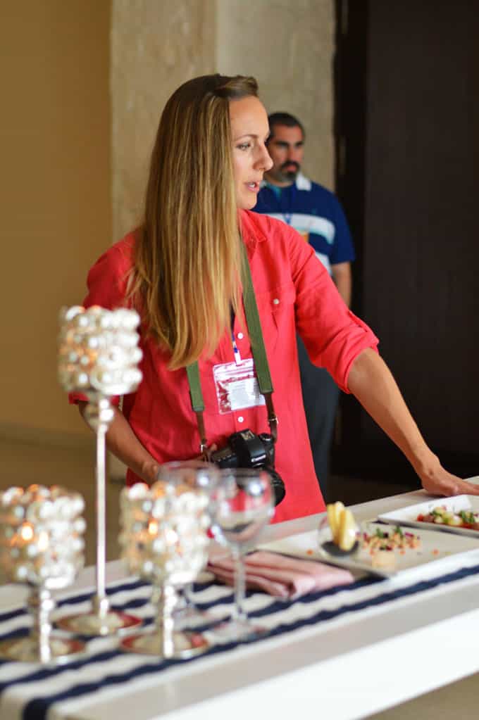 A woman with a camera standing by a table with food.