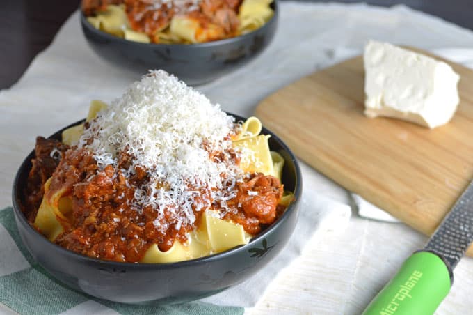 Closeup of pasta bowls with meat sauce and grated cheese.