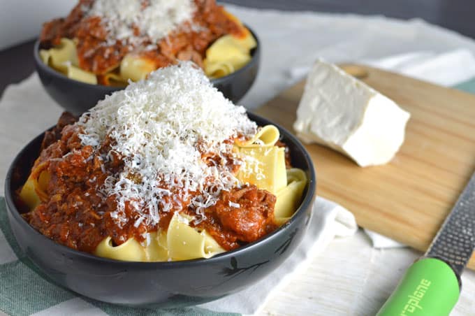 Bowls of pasta with meat sauce and grated cheese.