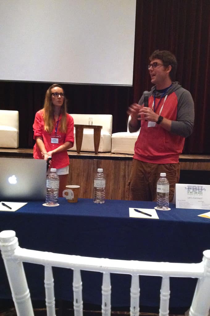 Two people standing behind a table with microphones.