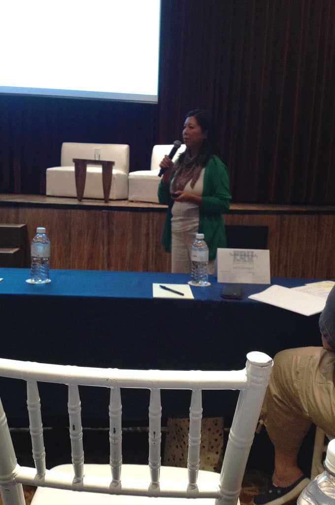 A woman standing behind a table with a microphone.