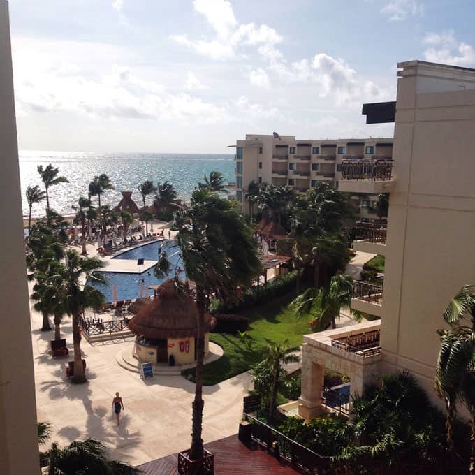 A view of a resort with pools and the ocean in the background.