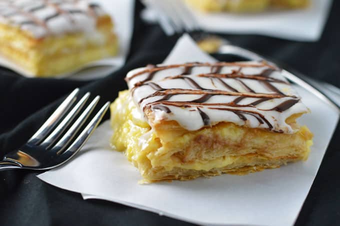 A slice of mille feuille on a parchment square with a fork.