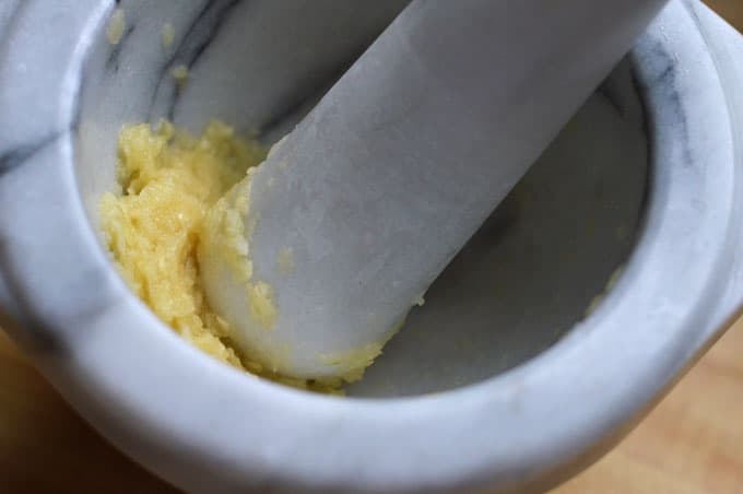 Close up of garlic paste in a mortar and pestle.