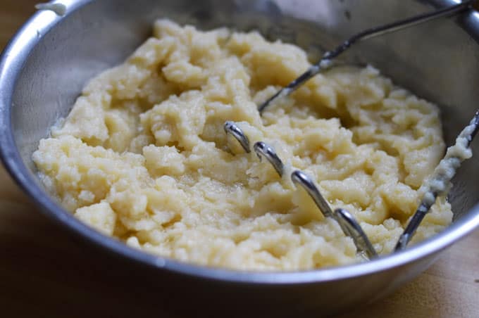 Potato being mashed in a bowl.