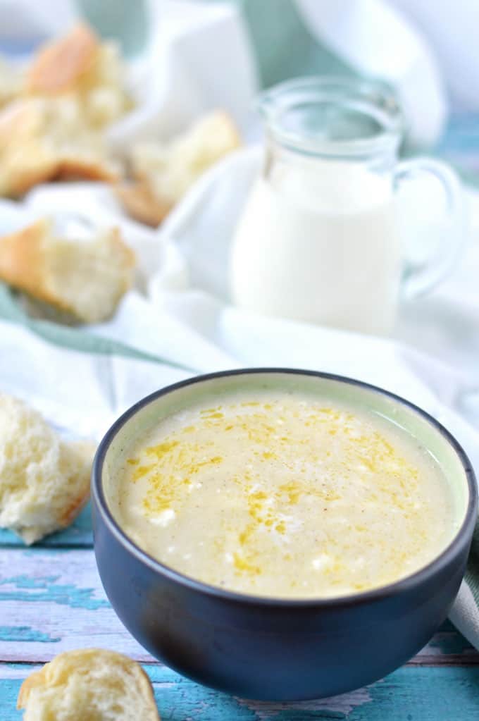 Closeup of soup in a bowl with bread and milk in the background.