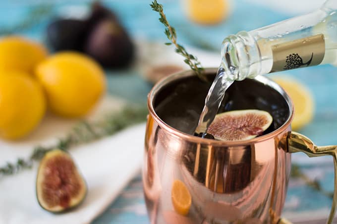 A closeup of ginger beer being poured into a copper mug.