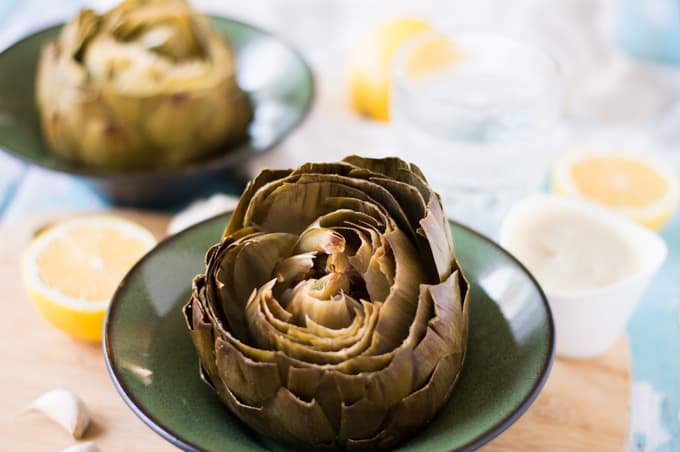 A roasted artichoke in a bowl.