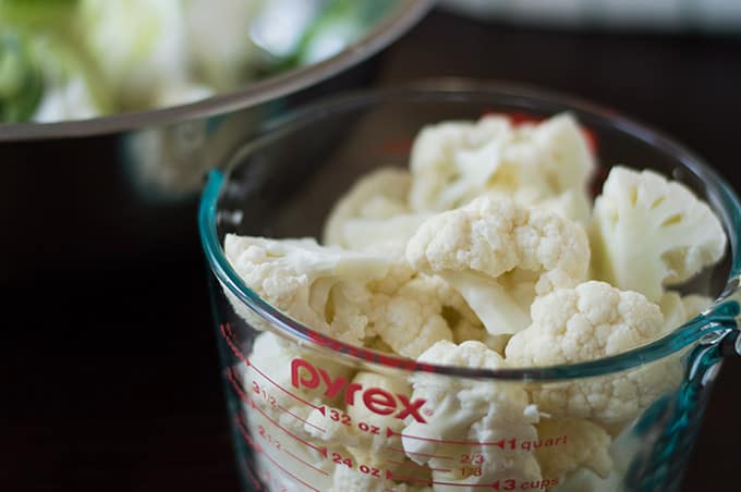 A close up of cauliflower florets in a measuring bowl.