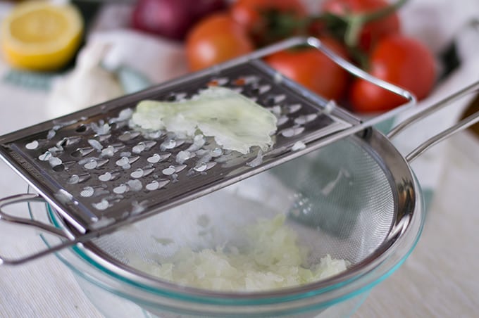 A bowl of grated onion with a grater on top.