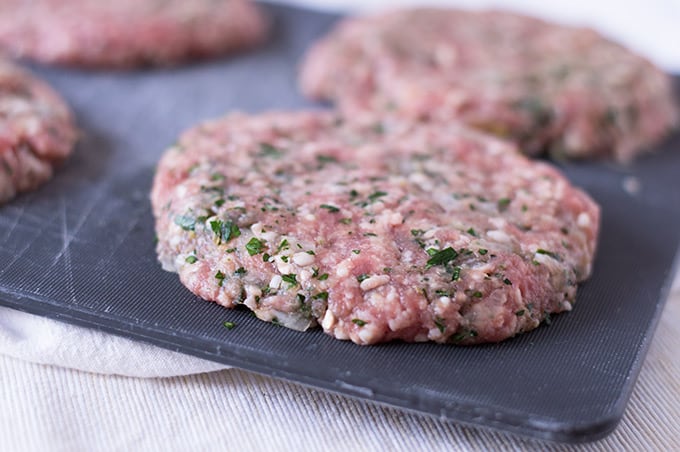 A close up of burger patties on a cutting board.