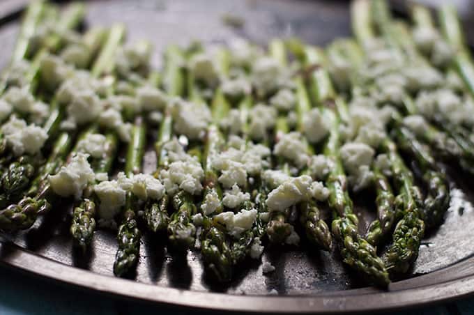 Asparagus topped with feta on a baking tray.