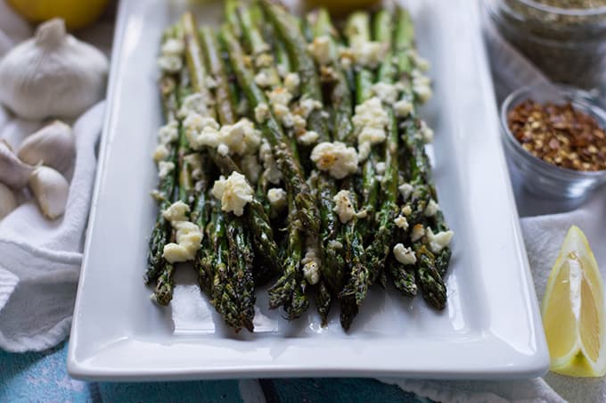 Roasted asparagus topped with feta on a plate.