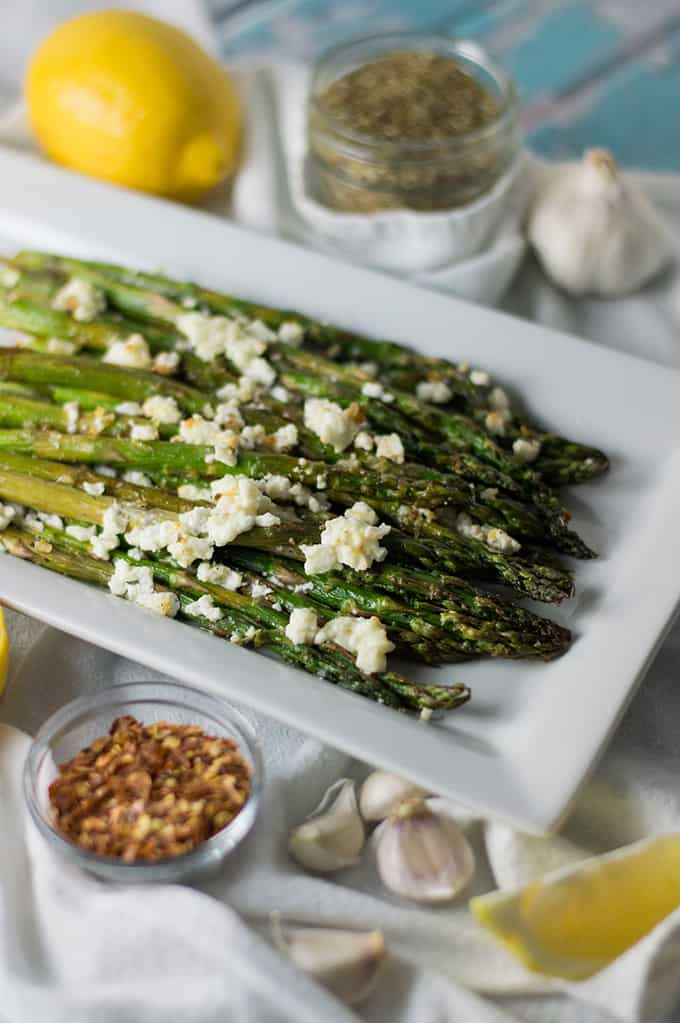 A plate of roasted asparagus topped with feta cheese.