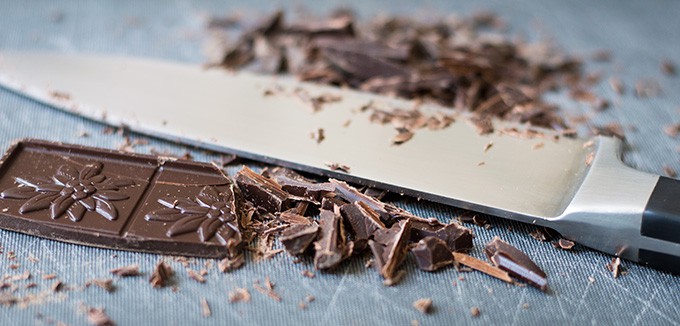 Chopped chocolate on a cutting board with a chef\'s knife.