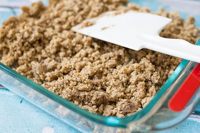 Crumbly pie crust in a baking dish with a plastic spatula.