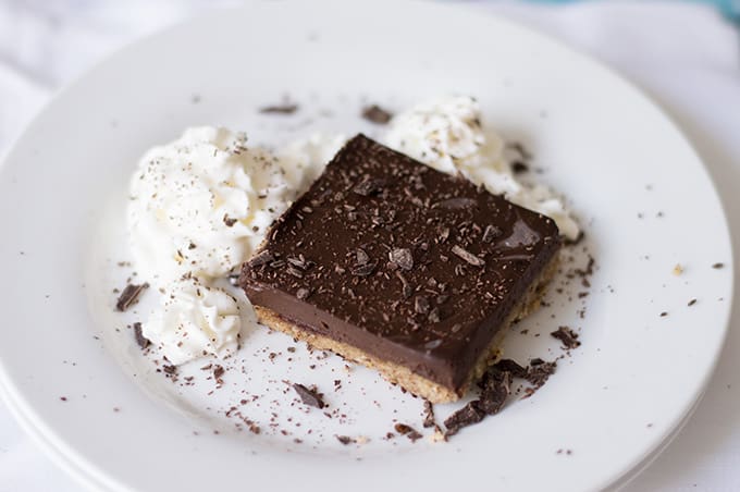 A slice of chocolate pie bar on a plate with whipped cream.