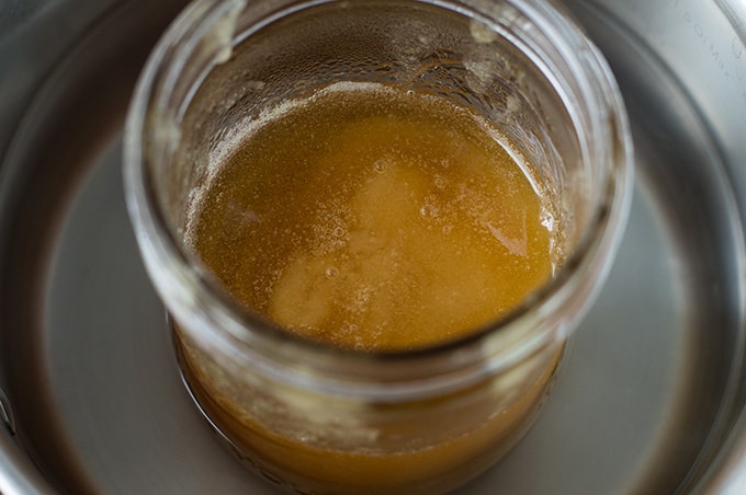 Close up of a jar of crystallized honey melting in a pot of water.