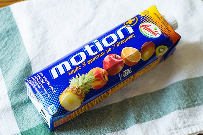 A carton of juice laying down on a fabric-lined table.