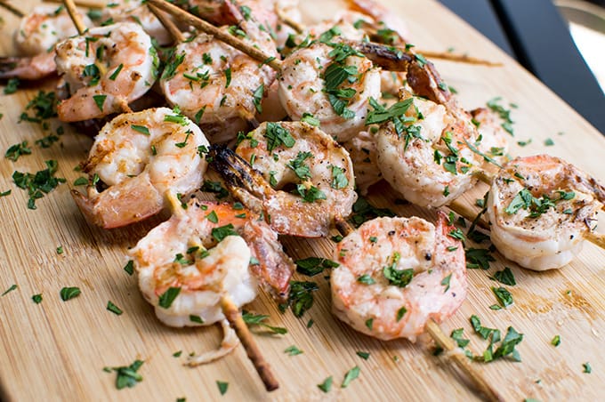 Skewered grilled shrimp on a cutting board.