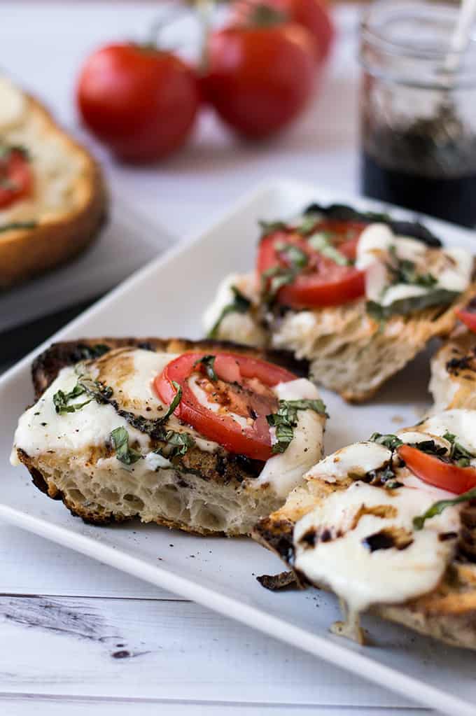 A plate of open-faced cheese and tomato sandwiches.