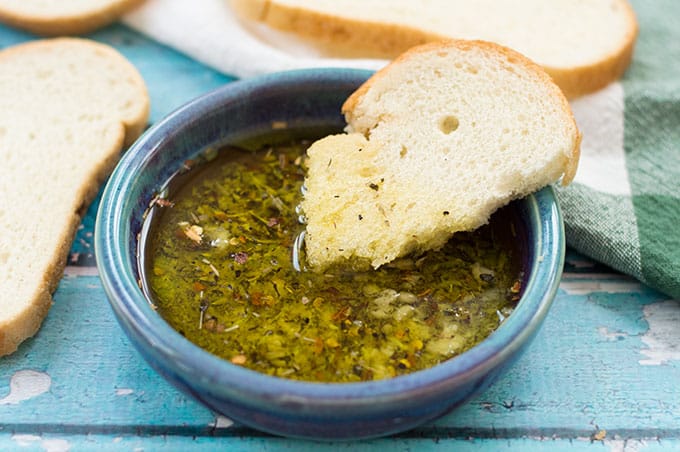 A close up of a slice of bread dipped in a garlic oil.