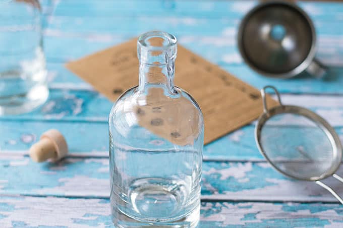 A glass of water on a table, with a funnel and fine mesh sieve.