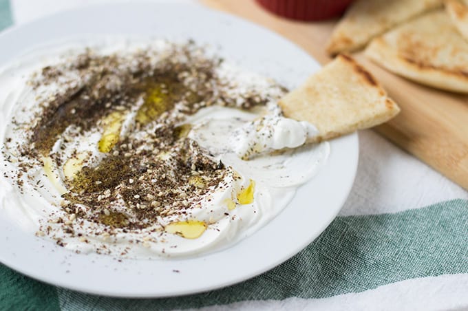 Spiced yogurt on a plate with pita bread.