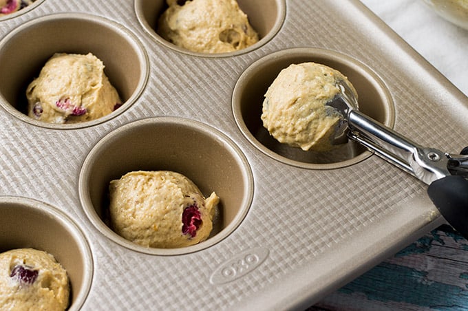 Batter being scooped into a muffin tin.